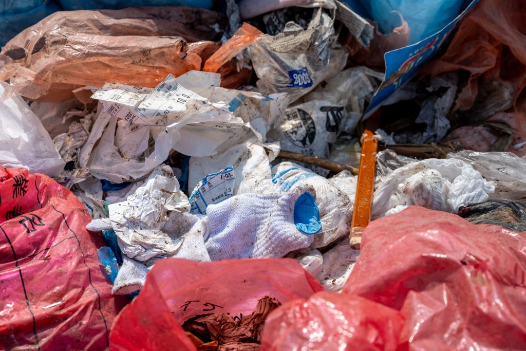 ごみの山の一部をアップした写真。ごみ袋から飛び出た軍手や紙ごみ、プラスチックごみなどが見える