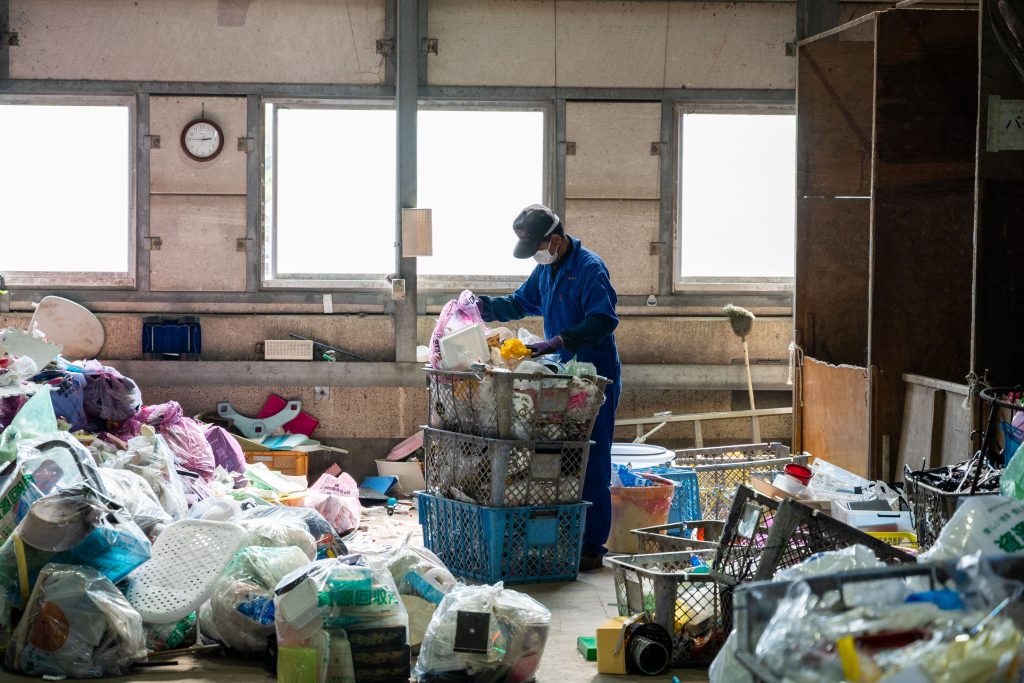 作業員の方が山積みになったプラスチックごみを選別している