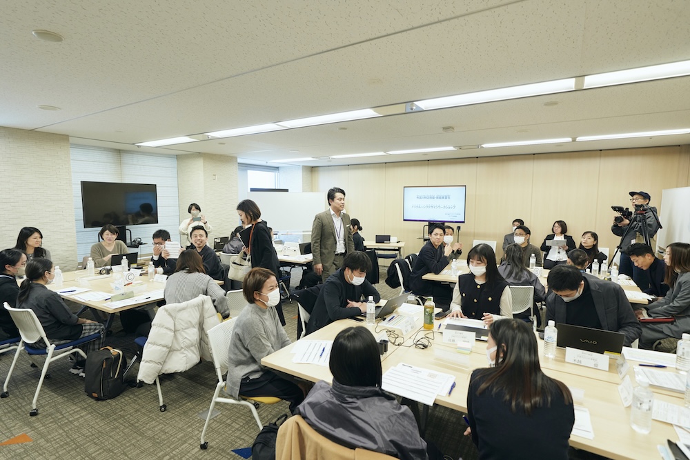 ワークショップ会場の中心で、丸山さんが全体に向けて説明している