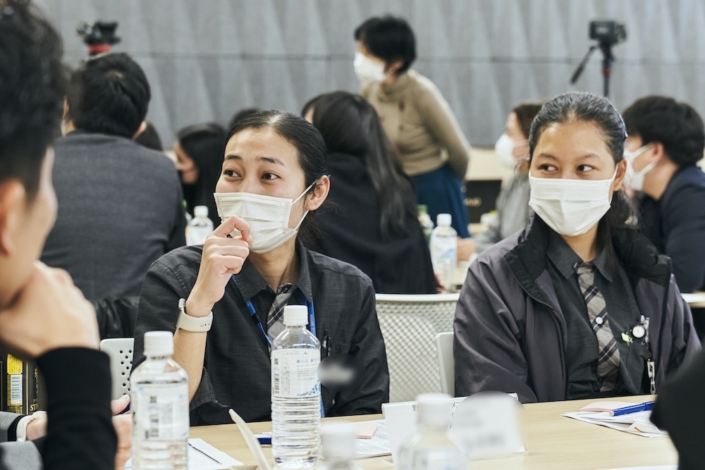 グループワークで外国人女性ワーカーが日本人社員に話している