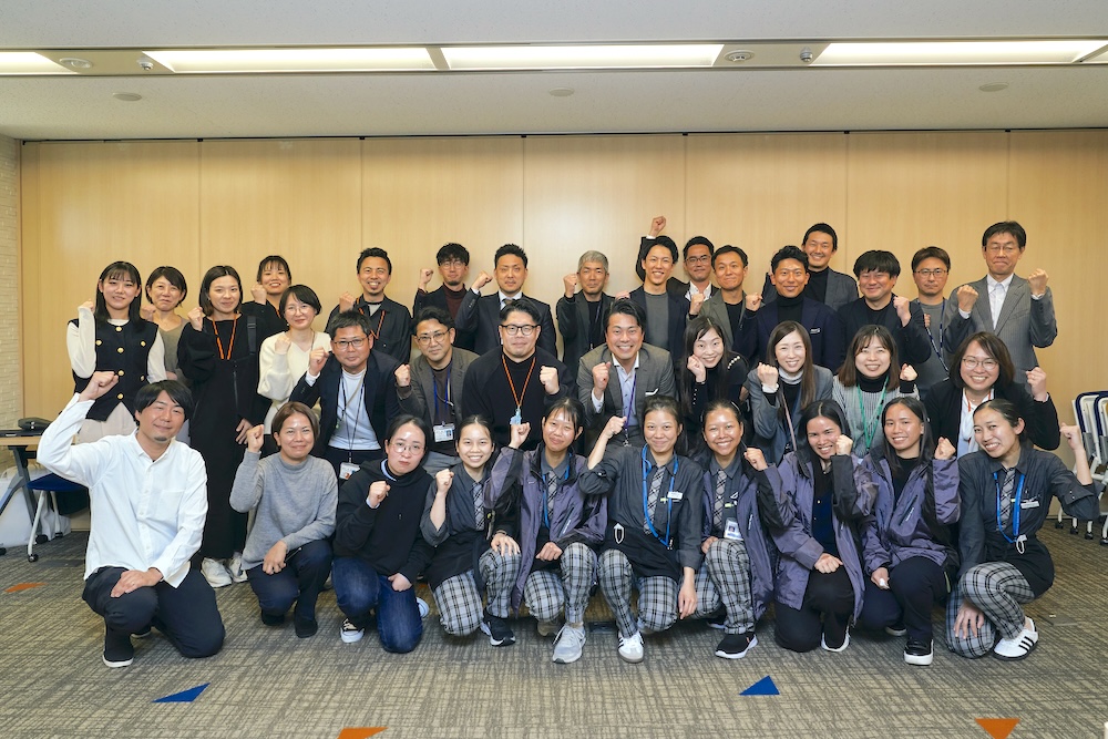 ワークショップ後の集合写真。外国人ワーカーと日本人社員、ワークショップをファシリテートしてくれたタキザワさんらが笑顔でポーズ
