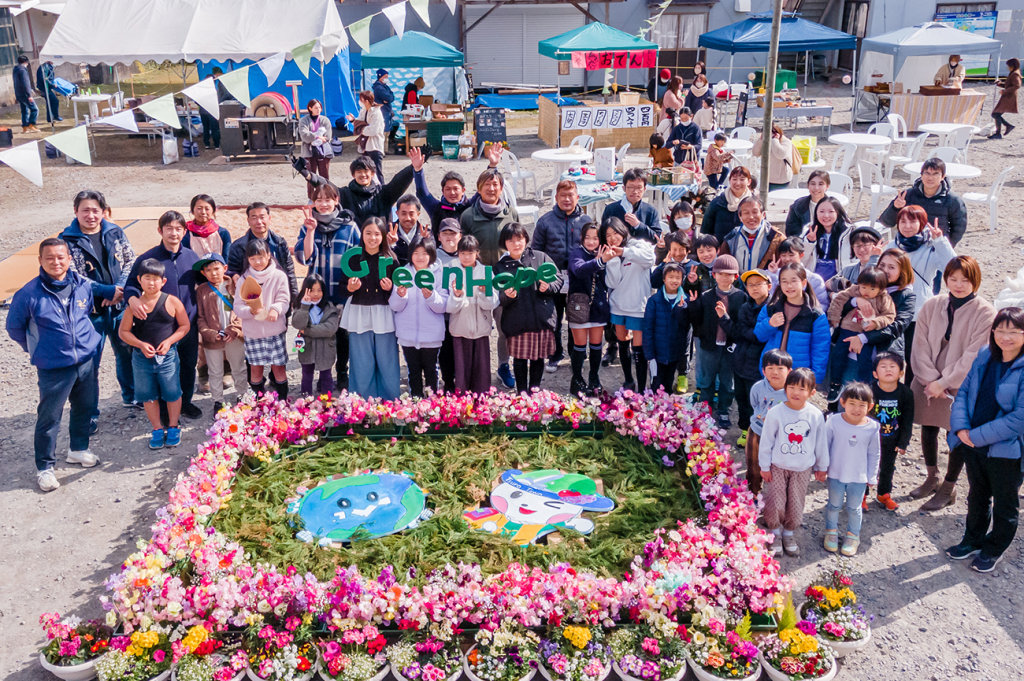 「Green Hope」の看板を持つ子どもや大人たちが笑顔で集合写真に収まっている様子