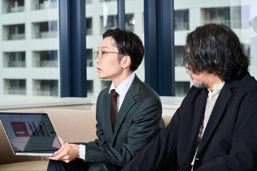 パソコン画面を見せながら、デザインについて説明している様子。