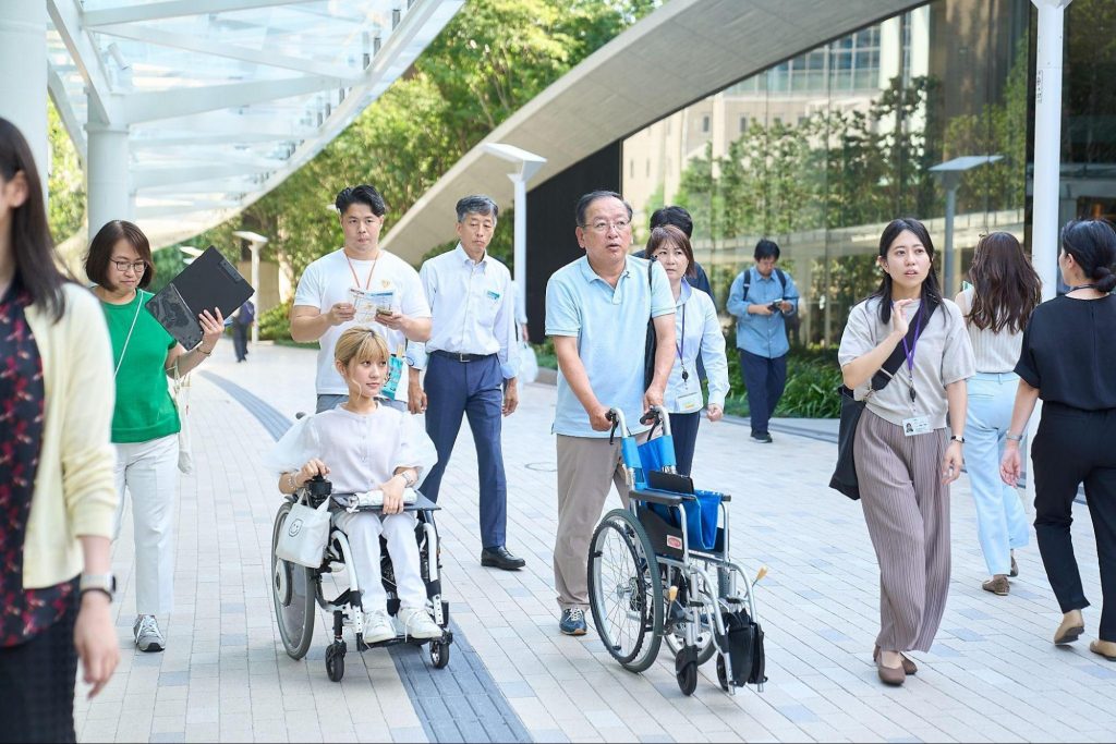 大門駅周辺を車いすで移動しながら、BFSまでのルートを調査する新井グループCEOと参加者