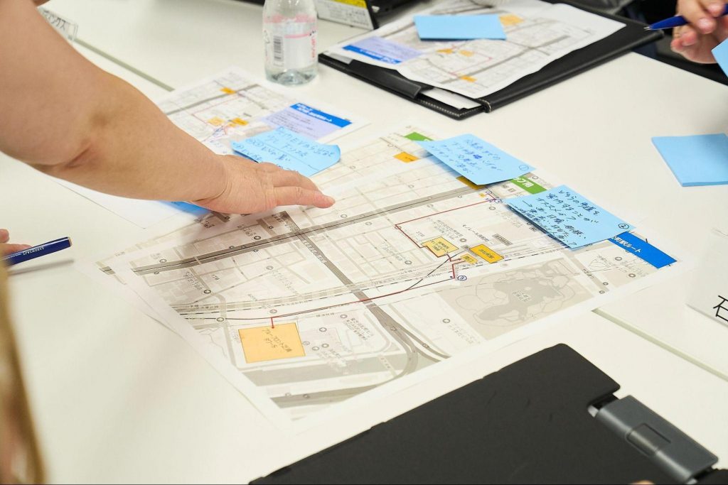 机に広げた地図に付箋や写真を貼り付けながらアクセシビリティマップを作成している様子