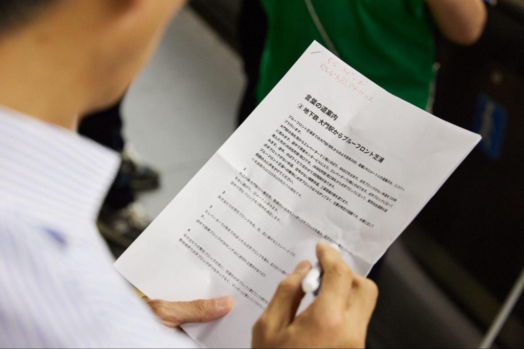 視覚障がい者向けの言葉の道案内が印刷された紙を、手に持って確認している様子