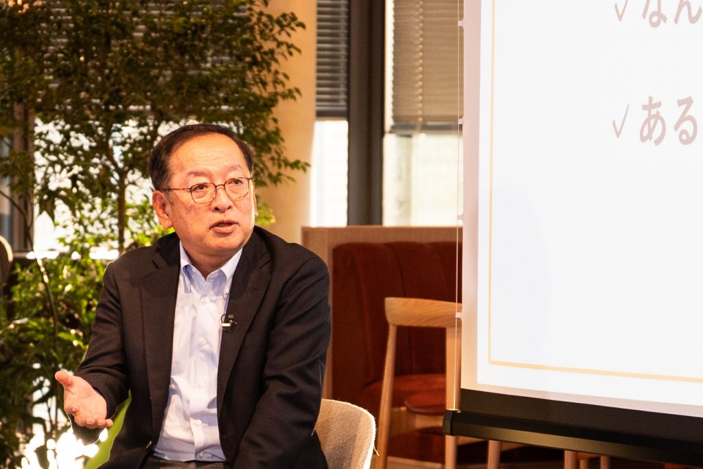 Group CEO Arai speaking on stage with hand gestures